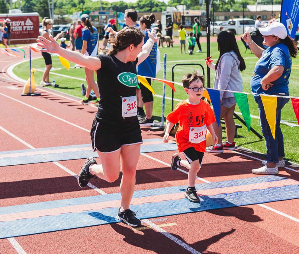 A mother cheers for her young son as they cross the finish line of a race together.