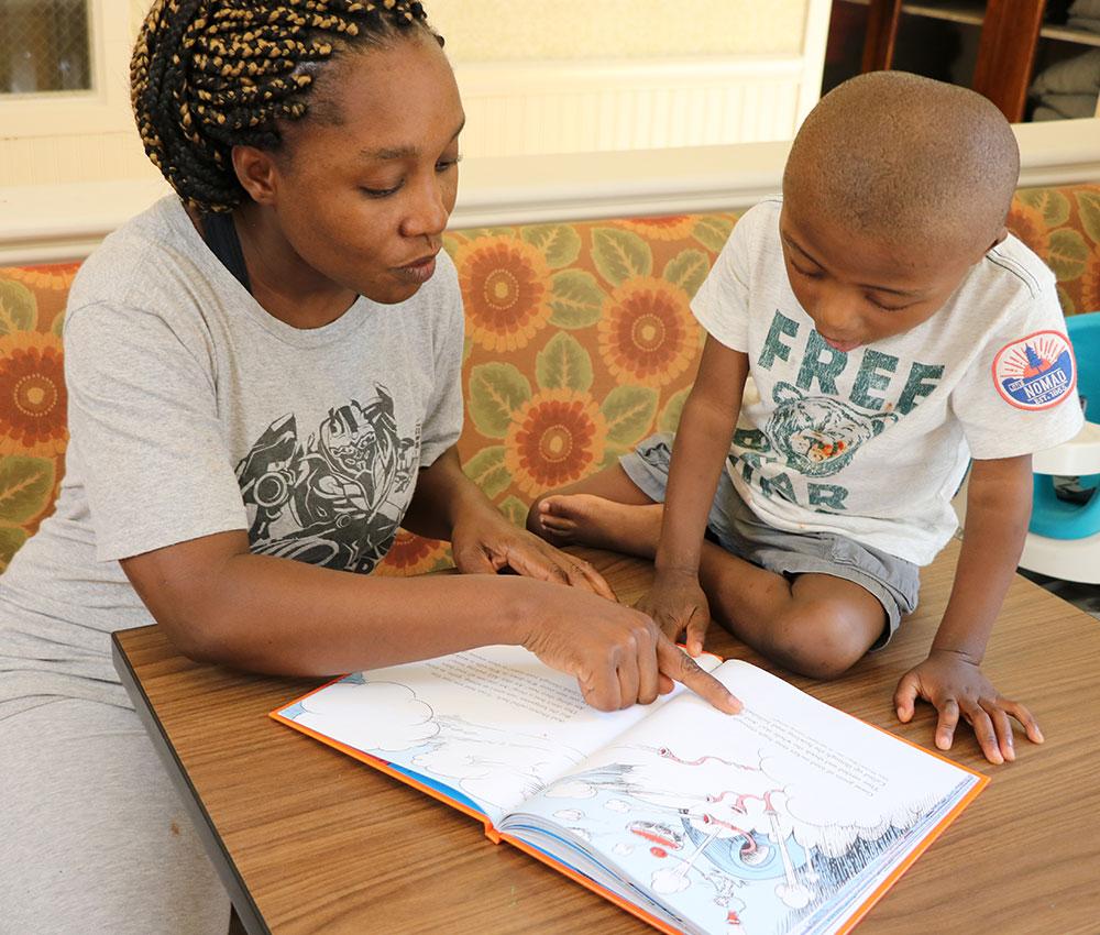 A mom and her son read together in the dining room at the Ronald McDonald House