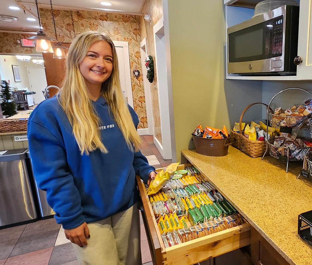 A volunteer poses near a neatly organized snack drawer at the Ronald McDonald House.