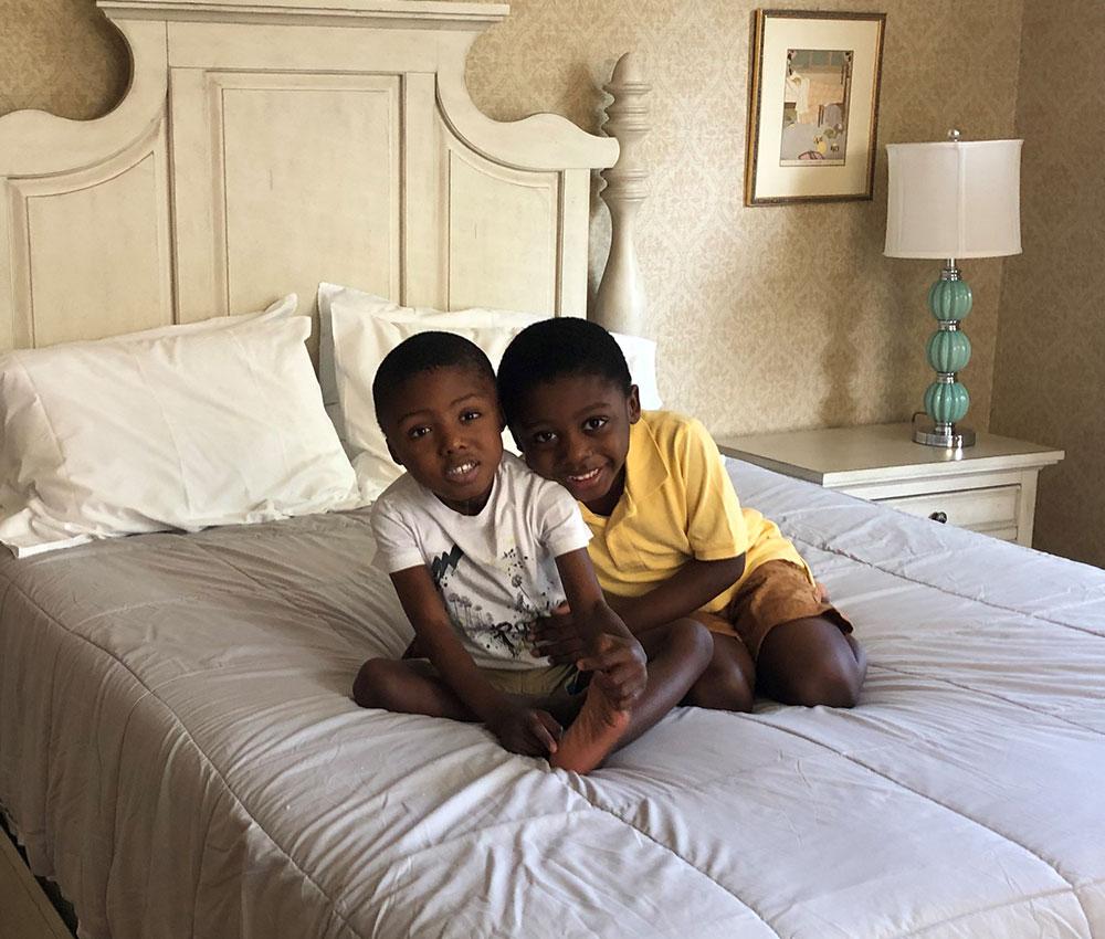 Brothers snuggle up on a large bed at the Ronald McDonald House