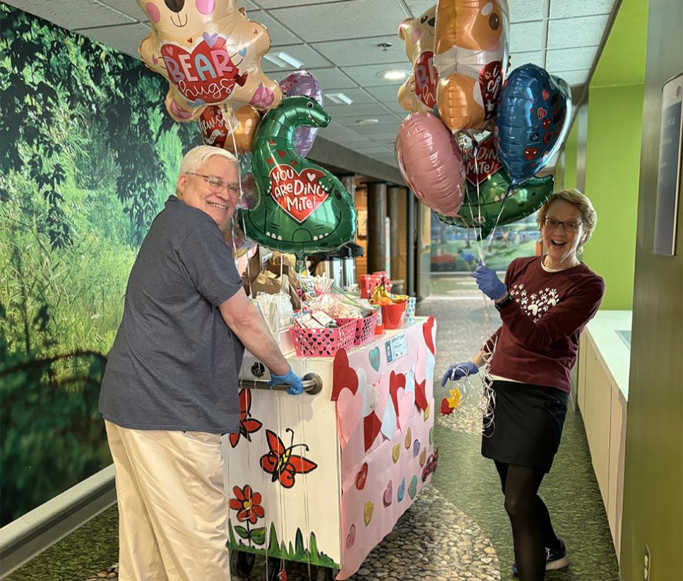 Volunteers push the Comfort Cart down the hall with balloons and decorations galore