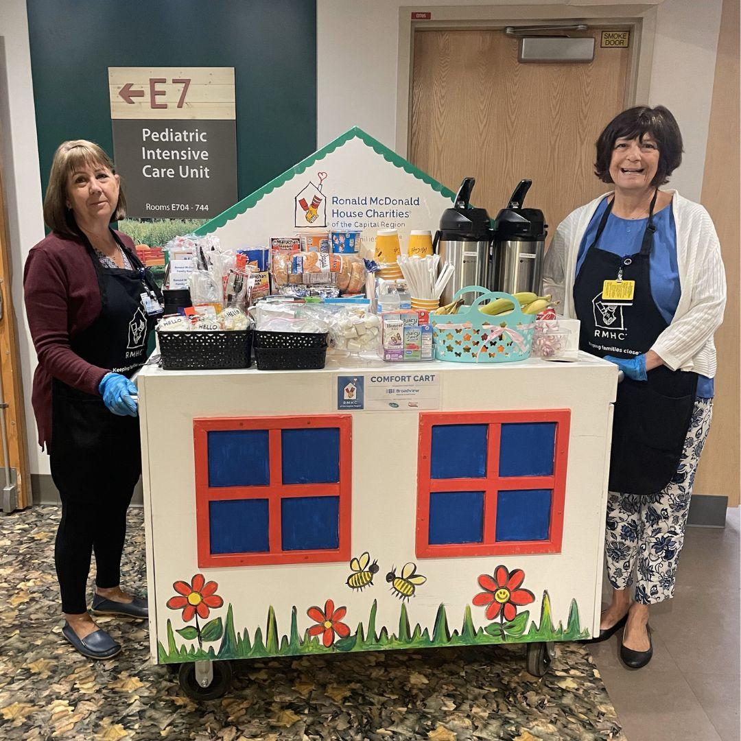 Two women maneuver the Ronald McDonald House Comfort Cart through the Pediatric ICU at Albany Med