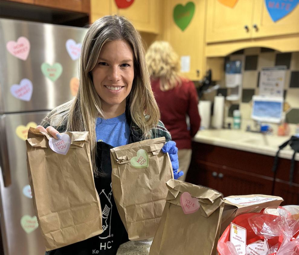 A volunteer holds up a few bagged lunches in the Ronald McDonald House Family Room decorated with hearts