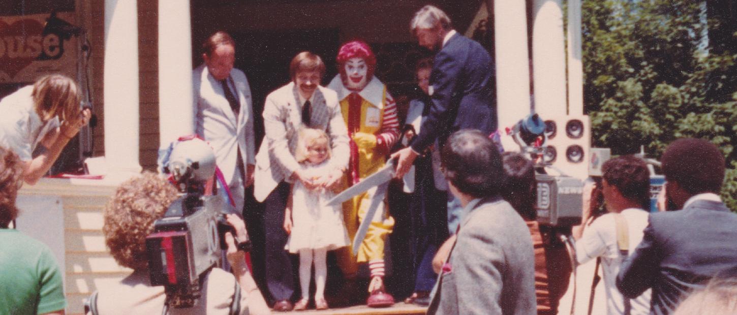 Group of people surrounds a young girl at ribbon cutting for the Albany Ronald McDonald House