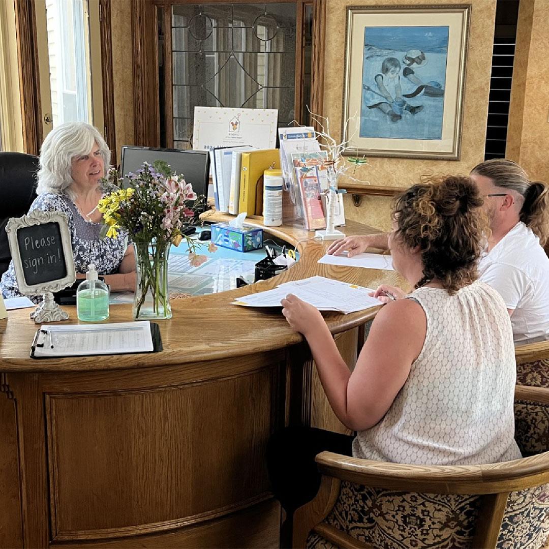 A volunteer sits with a couple checking in at the front desk of the Ronald McDonald House