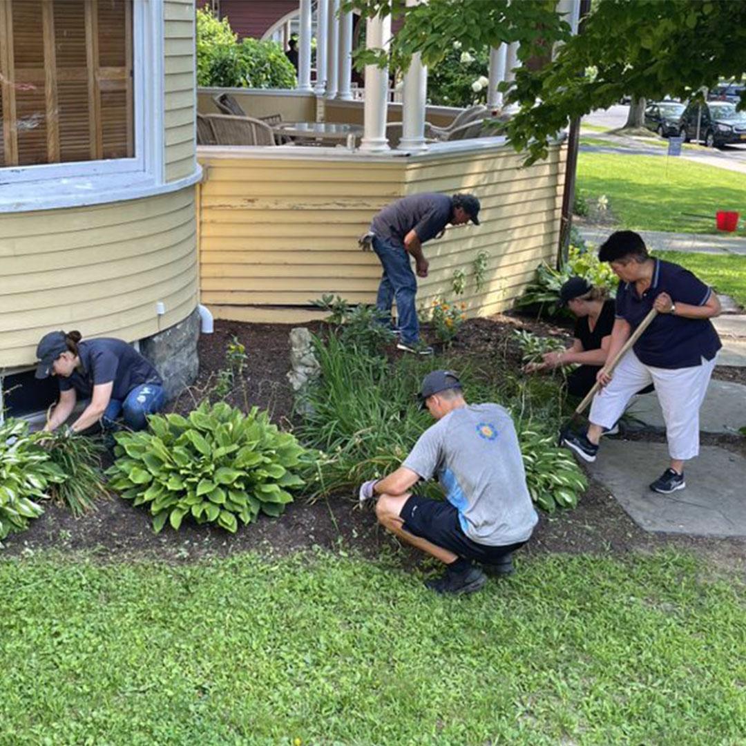 A group of volunteers does yard work around the Ronald McDonald House