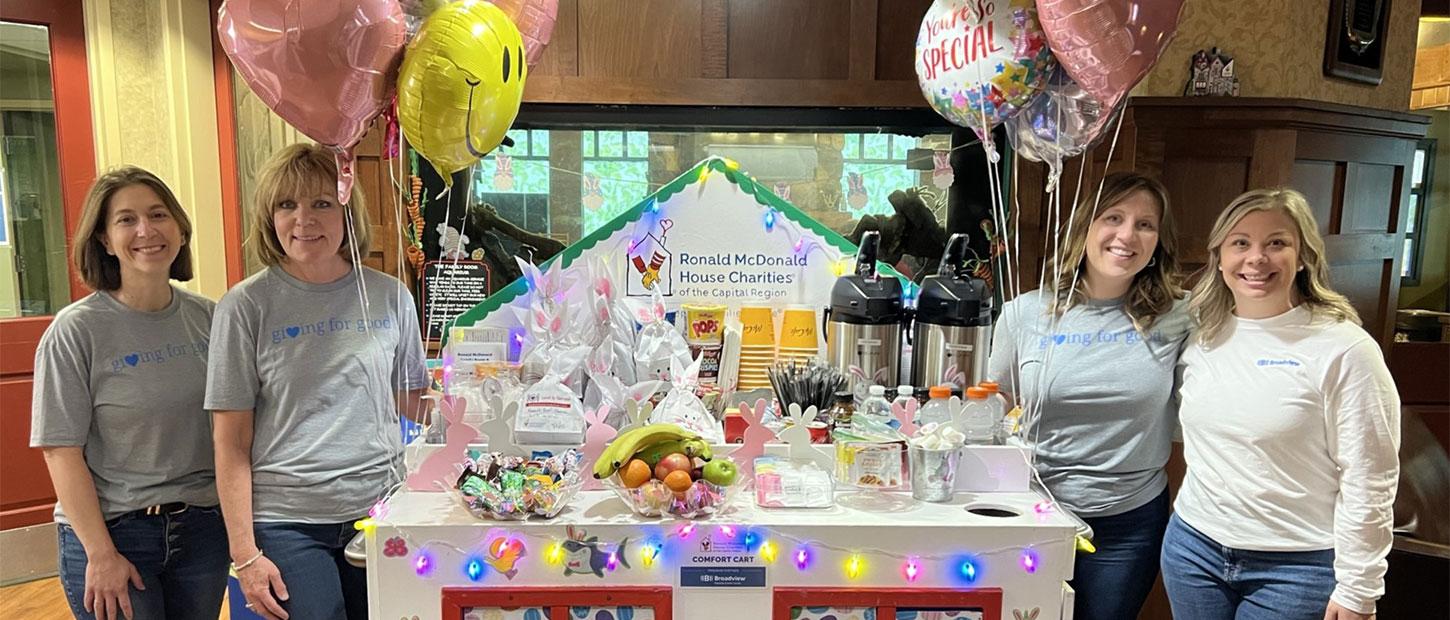 Four women pose around the Comfort Cart in the Ronald McDonald House Family Room at Albany Medical Center
