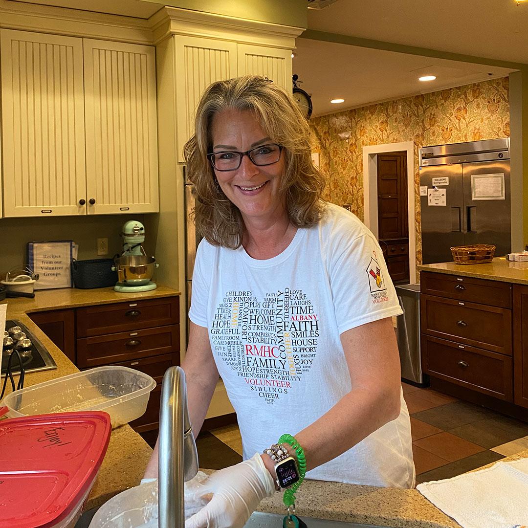 A House Warmer smiles while washing dishes at the Ronald McDonald House