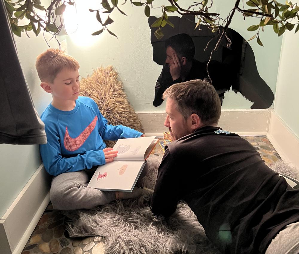Father and son reading a book in a nook at Krantz Cottage