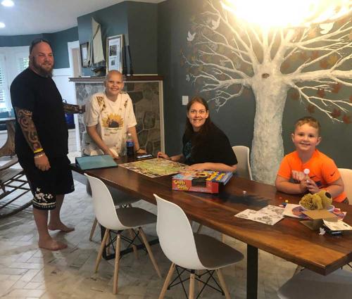 A family of four sits at a long dining table in Lake George playing board games together.