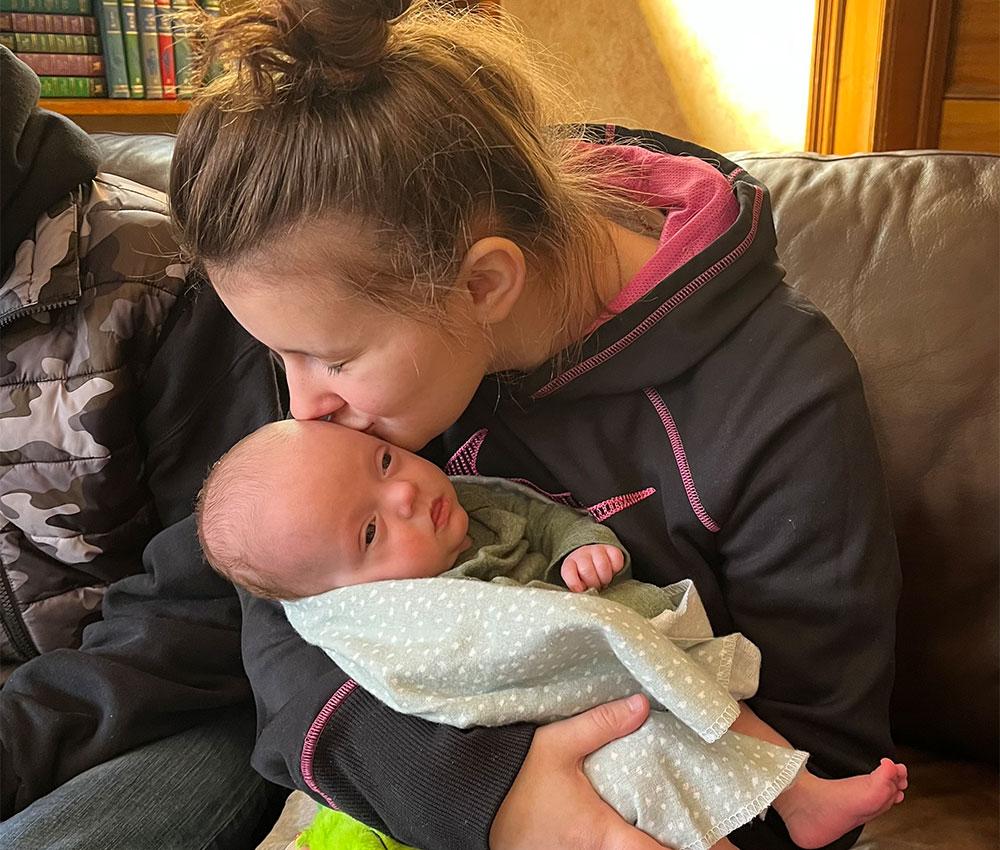 A mom kisses her baby's forehead while sitting on a couch in the Ronald McDonald House living room